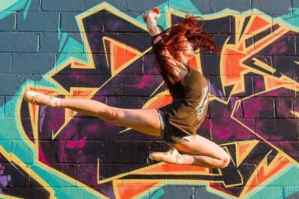 Nicki jumping in pointe shoes in front of a graffiti mural